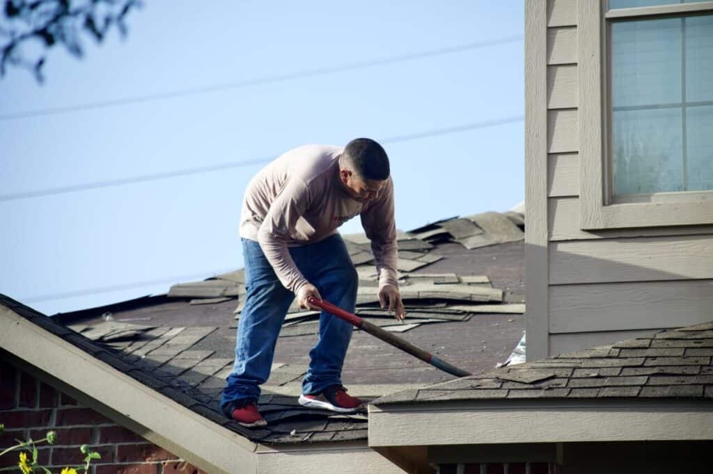 A man with a hammer on top of the roof